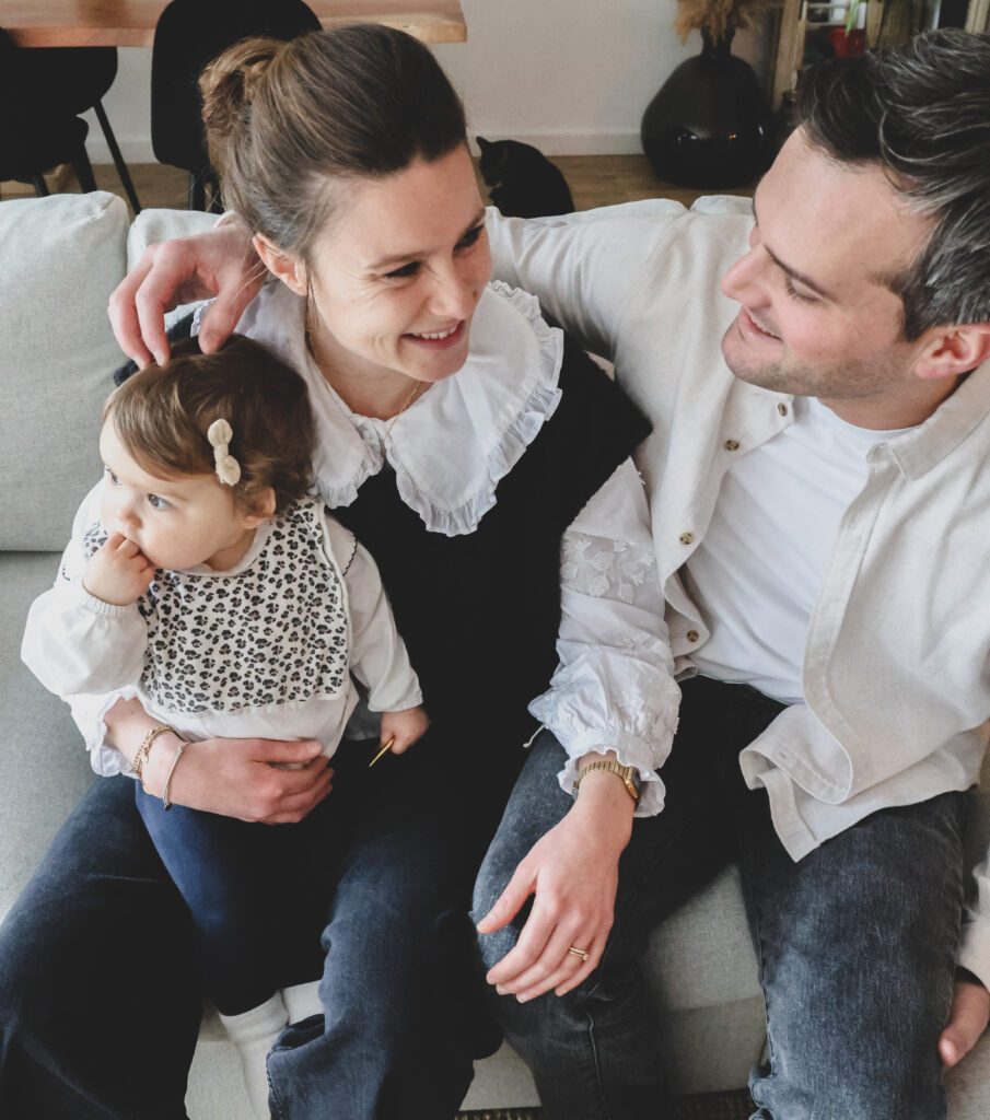 Un couple assis sur le canapé, leur petite fille sur les genoux