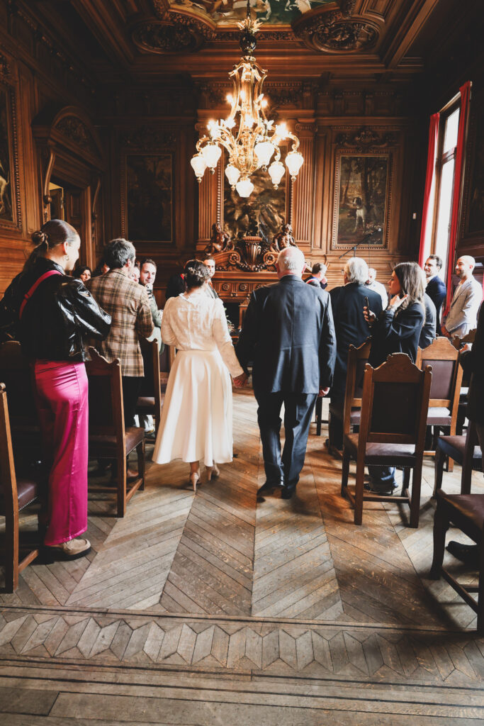 shooting photo mariage - a la mairie le jour du mariage, le père et la mariée de dos s'avancent vers l'autel